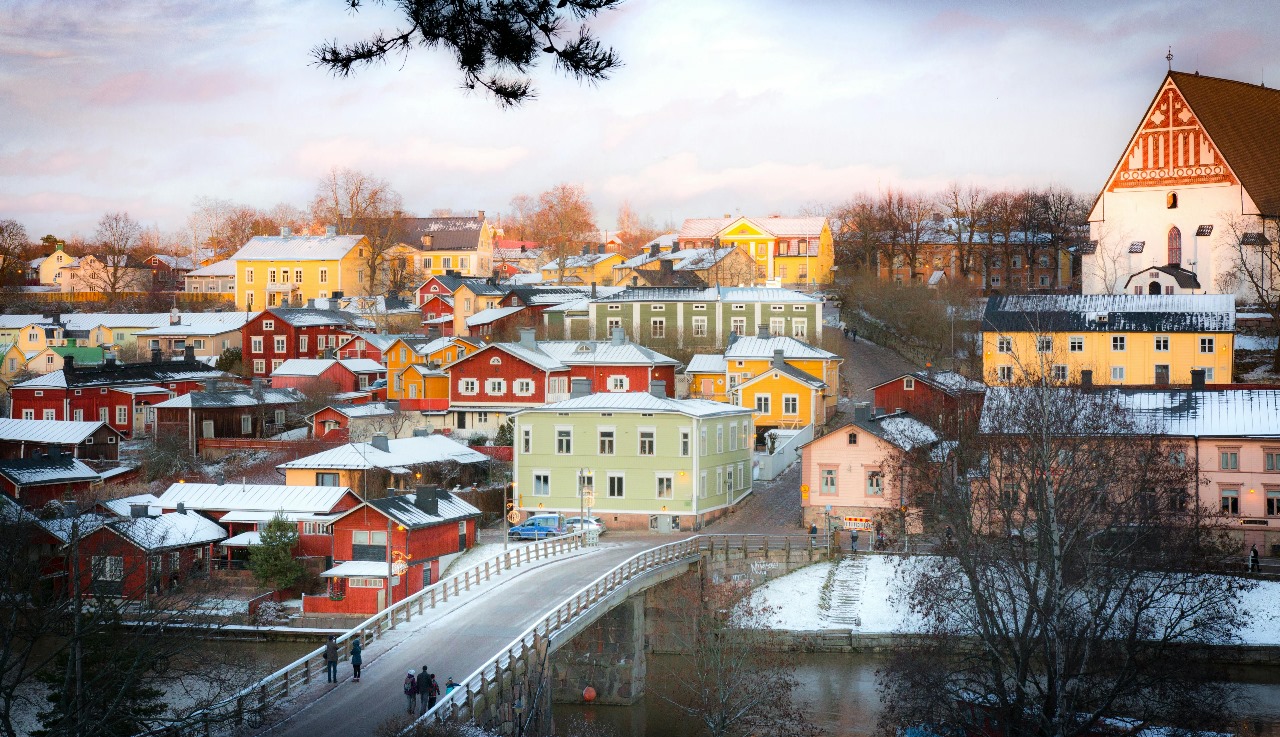 Picturesque Finnish town in winter with colorful wooden houses covered in snow and historic church, representing Finland's world-renowned education system and Nordic charm
