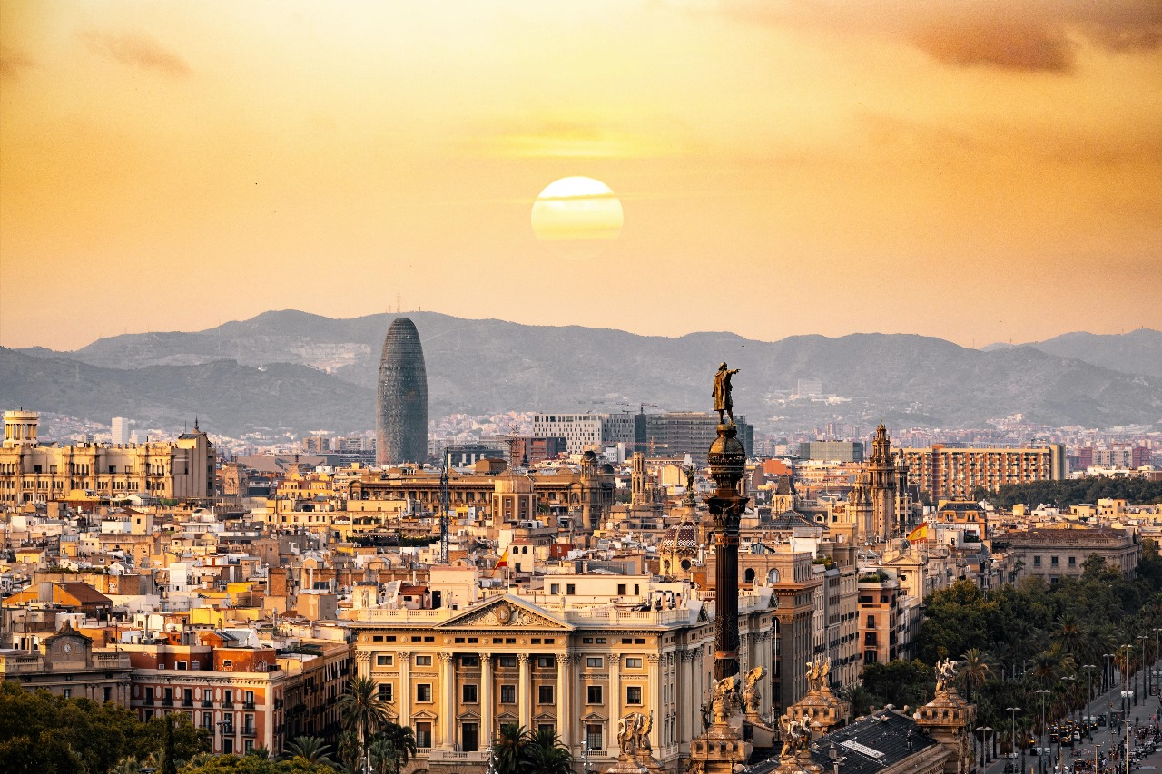 Barcelona's golden sunset skyline featuring Torre Agbar and historic architecture with mountains in the background, representing Spain's vibrant culture and excellent academic programs